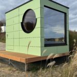 Außenansicht der grünen Design-Gartensauna mit Bullauge von PLUSGRAD