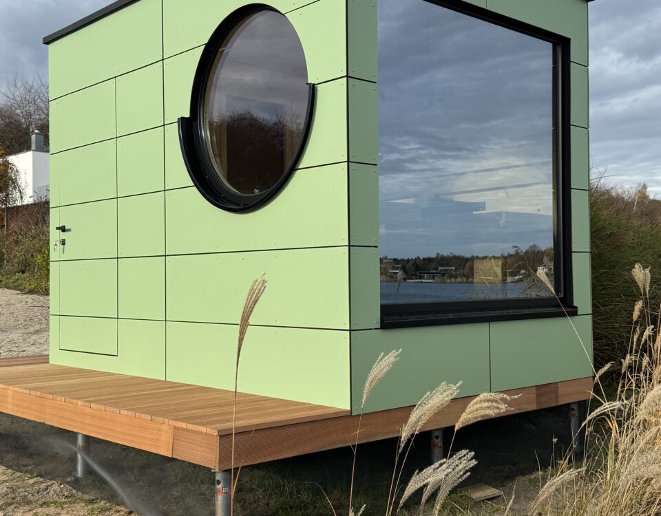 Außenansicht der grünen Design-Gartensauna mit Bullauge von PLUSGRAD