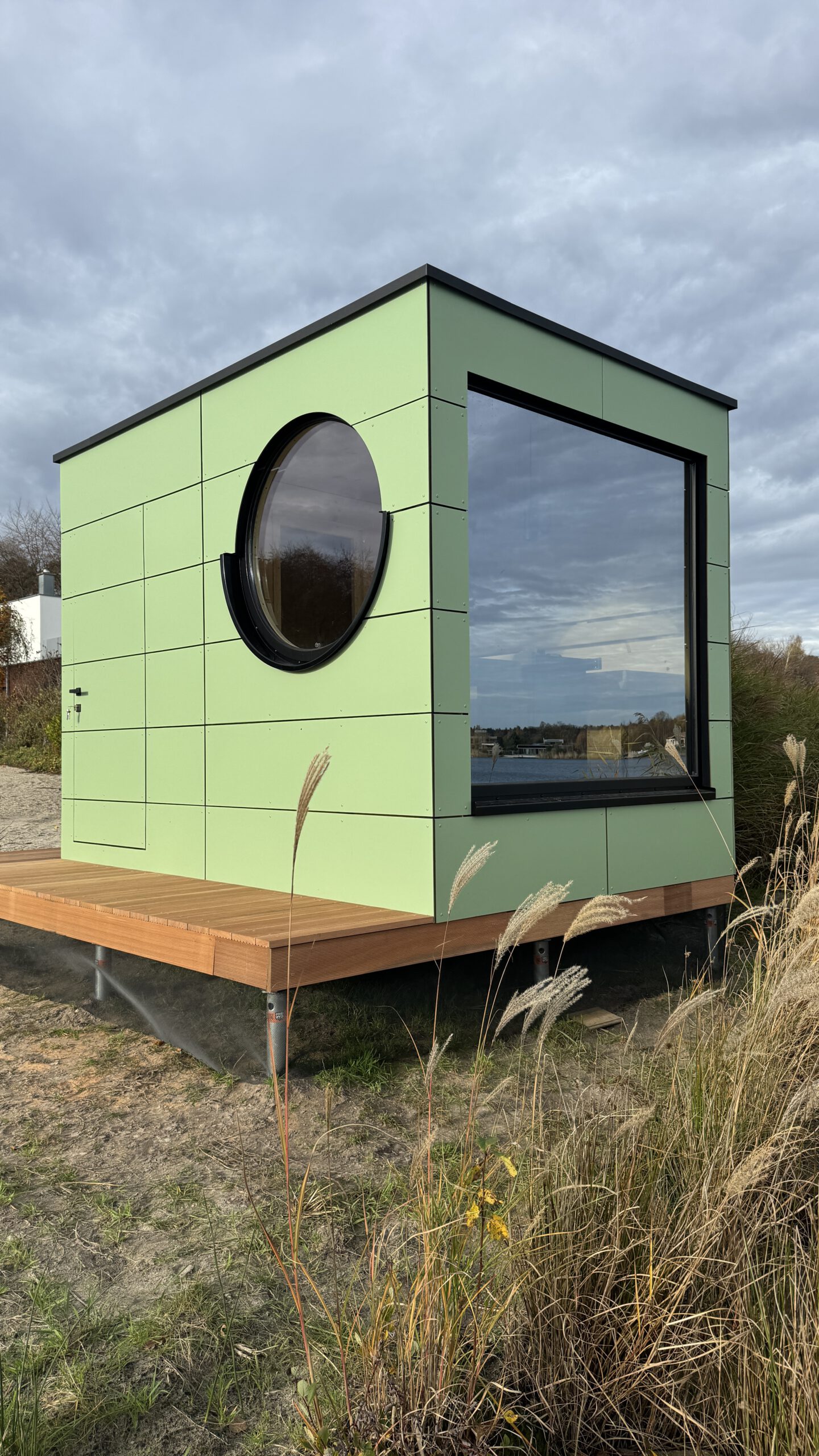 Außenansicht der grünen Design-Gartensauna mit Bullauge von PLUSGRAD